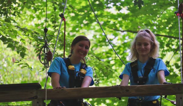 Two young women smiling while enjoying the aerial adventure park at Catamount Resort