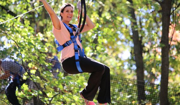 A happy woman smiling as she rides a zipline at the Aerial adventure park at Catamount Resort