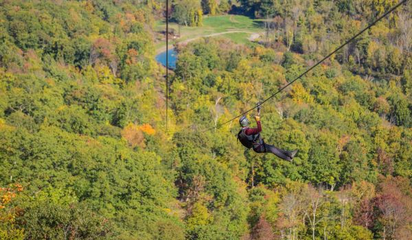 A man taking a relaxing ride down the zipline at Catamount Resort
