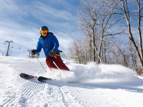 Skier in blue jacket carving a slope
