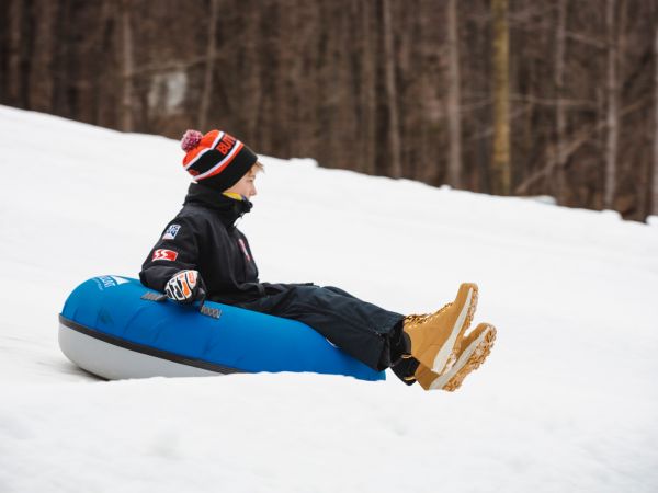 kid on snow tube sliding down hill