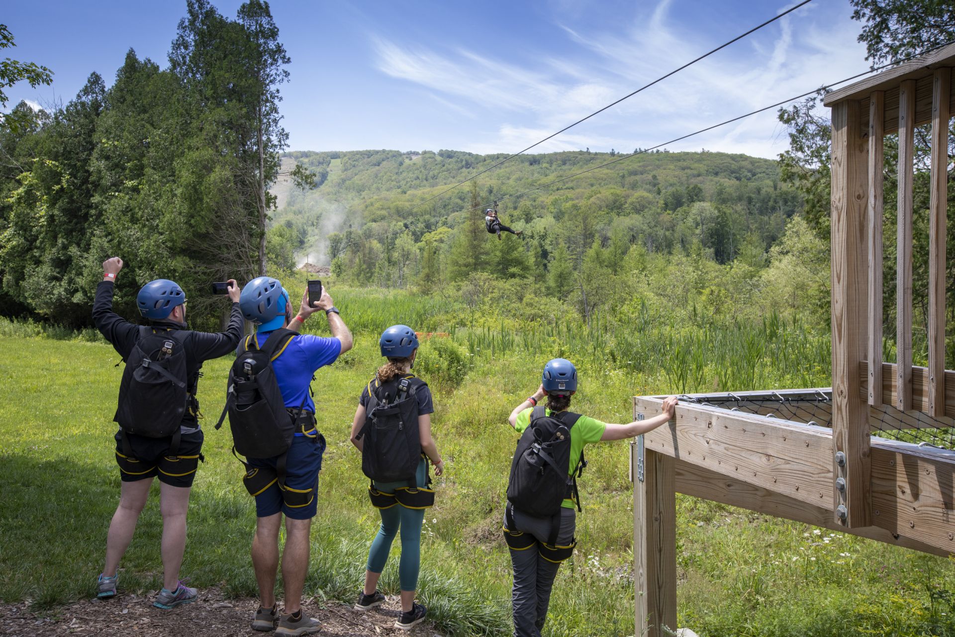 Four kids cheering on their friends and taking photos at the Catamount Resort Zip Tour